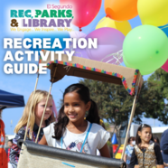 Girl in a booth with balloons smiling outside with kids