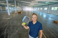 Brett Drogmund holding pickleball gear in a warehouse, photo by David Sprague, courtesy of LABJ