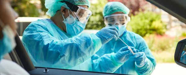 two people administering vaccination to woman in car 