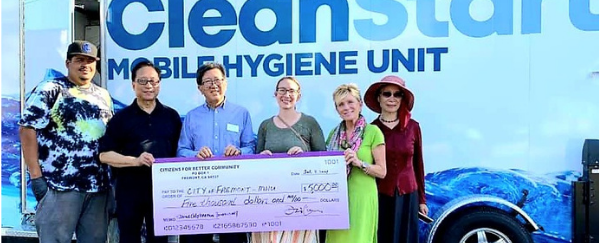 mobile hygiene unit and people presenting large check