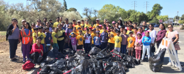 people standing in front of bags of trash collected
