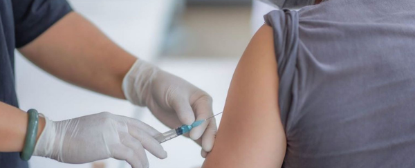 person administering COVID-19 vaccine in arm