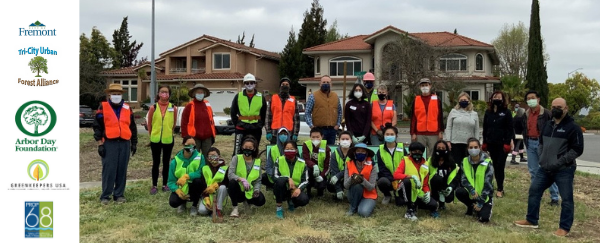 large group of volunteers in safety vests standing on grass in front of homes