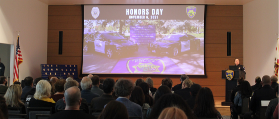 audience members looking at screen next to police officer speaking