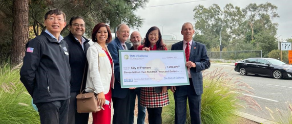 Elected officials standing together holding a big cardboard check