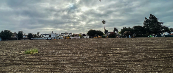 field of dirt with vehicles in the distance