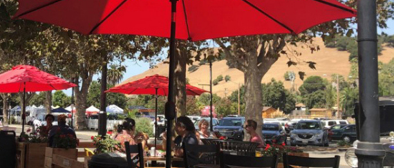 outdoor umbrellas and people eating at tables on sidewalk