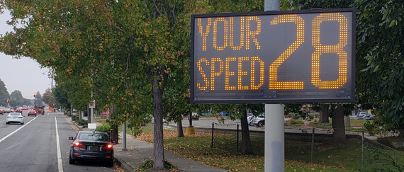 message board sign next to street with cars and trees. In text on sign: Your Speed 28