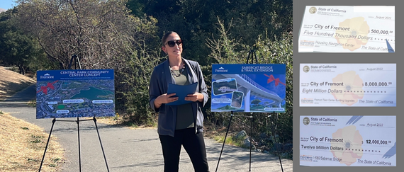 City employee standing in between two posterboards on easels along hiking trail with three symbolic checks presented