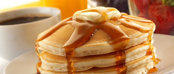 pancakes on plate with slab of butter and syrup with coffee in mug