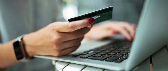 hand holding a credit card and entering info into laptop