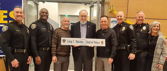 Former Police Chief Craig Steckler holds honorary plaque surrounded by members of Fremont Police Department, friends, and family