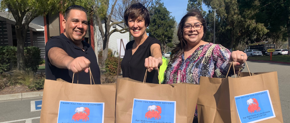 employees holding crab feed to-go bags in the parking lot