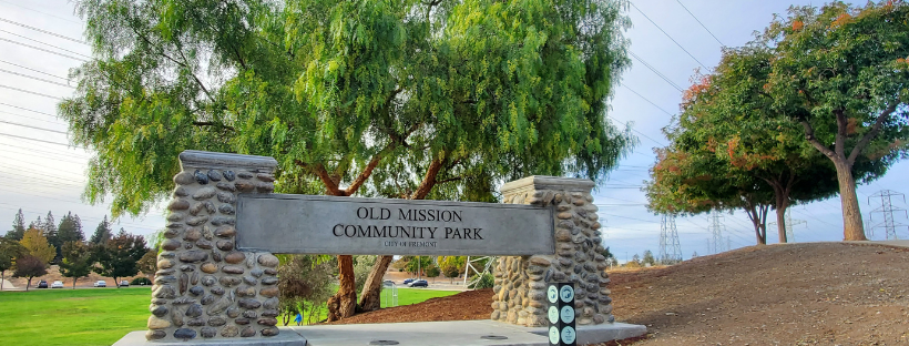 Old Mission Community Park stone sign in park with trees and grass