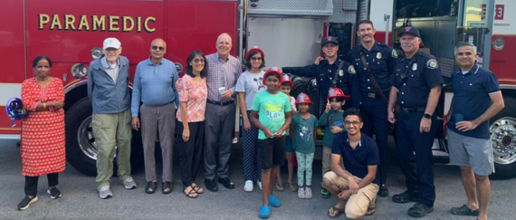 community members at Fremont National Night Out party standing in front of fire engine with Fremont Fire Department firefighters