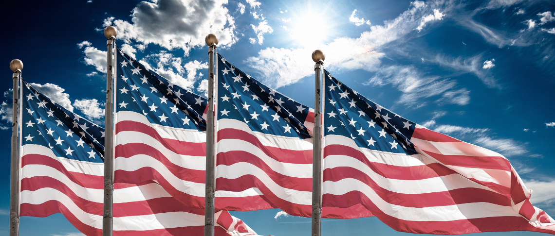 four American flags flying with blue sky and clouds