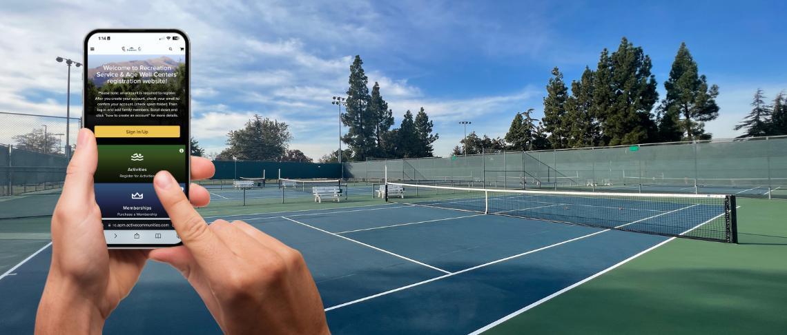 hands holding smart device with online registration screen and tennis courts in the background