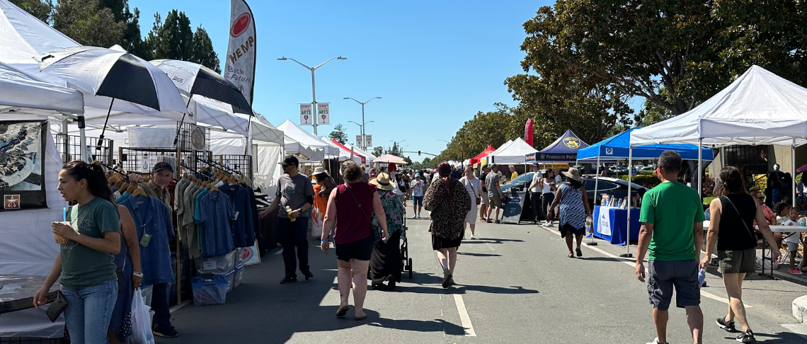 event attendees walking on street and talking to vendors in booths