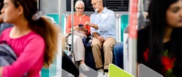couple on an AC Transit bus looking at their mobile device near other passengers