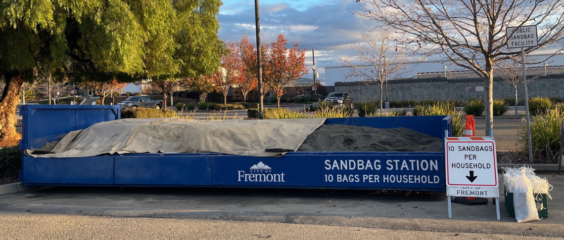 sandbags, sand, shovel and 10 sandbags per household in text on sign