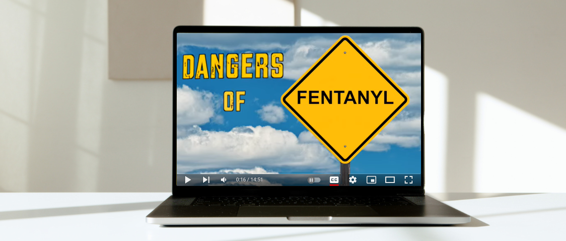 laptop on counter with image of sky and clouds and text that reads 'Dangers of' and yellow sign with Fentanyl in text
