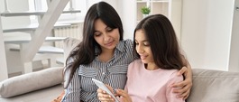 mother and teen sitting on a couch looking at a device