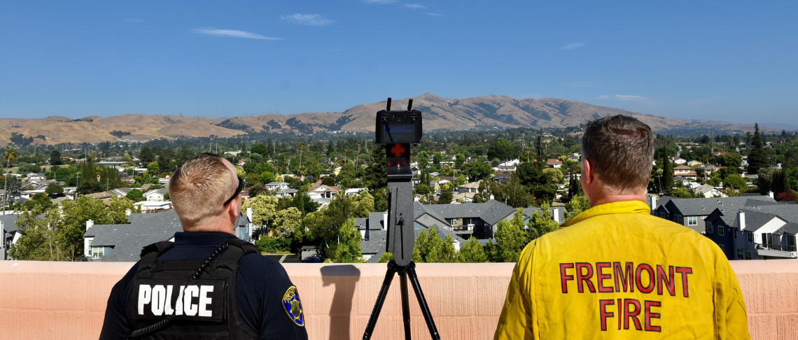 police officer and firefighter operating an Unmanned Aerial Vehicles (UAVs) as Drone as First Responder with hills in the background