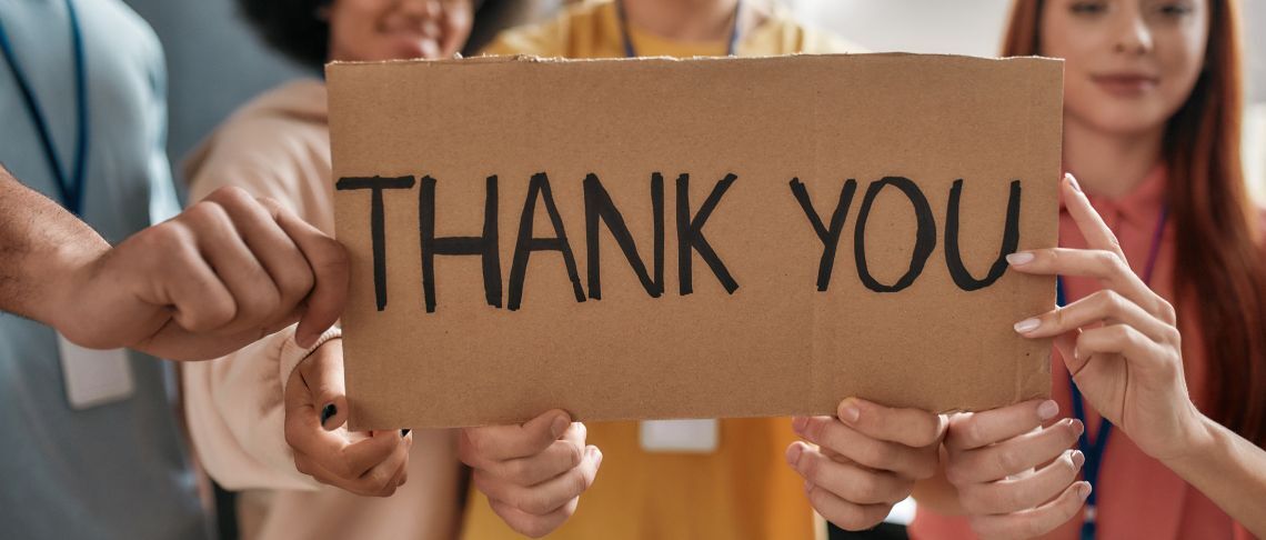 People holding a sign that reads Thank you