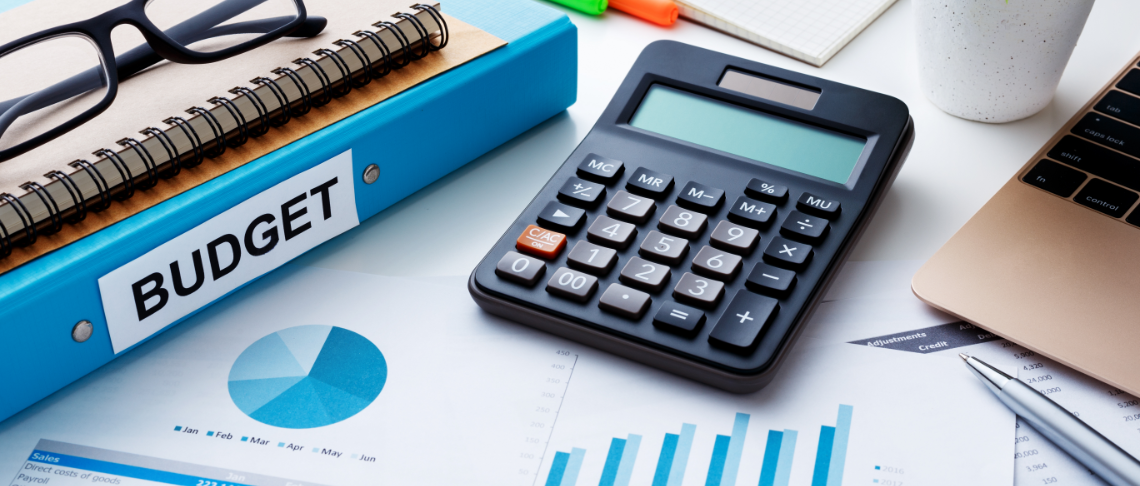 A financial document on a table with a pen, calculator, coins, and glasses laying on top of it.