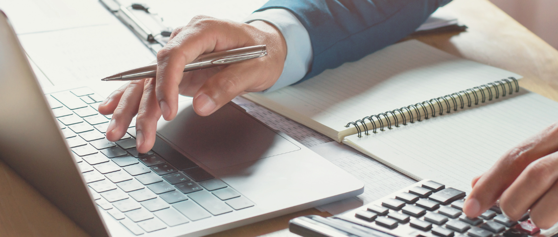 person typing on laptop and using a calculator