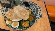 Tray of curries and sides with bread