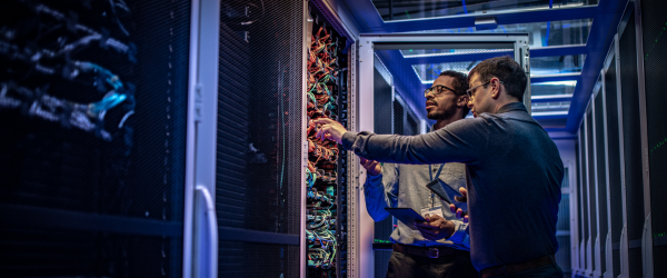 Two men discussing and examining the back of an AI server rack