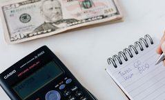 Calculator, stack of cash, and a notepad
