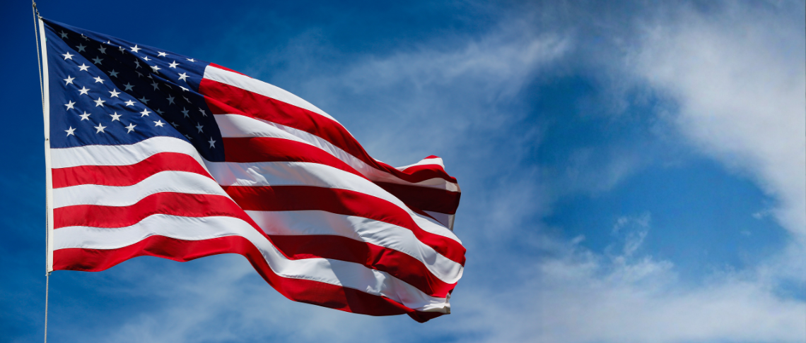 American flag waving prominently against a partly cloudy blue sky