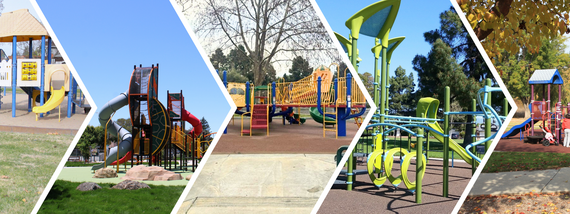 Wide view of a colorful playground with slides, climbing structures, and swings under a clear blue sky.