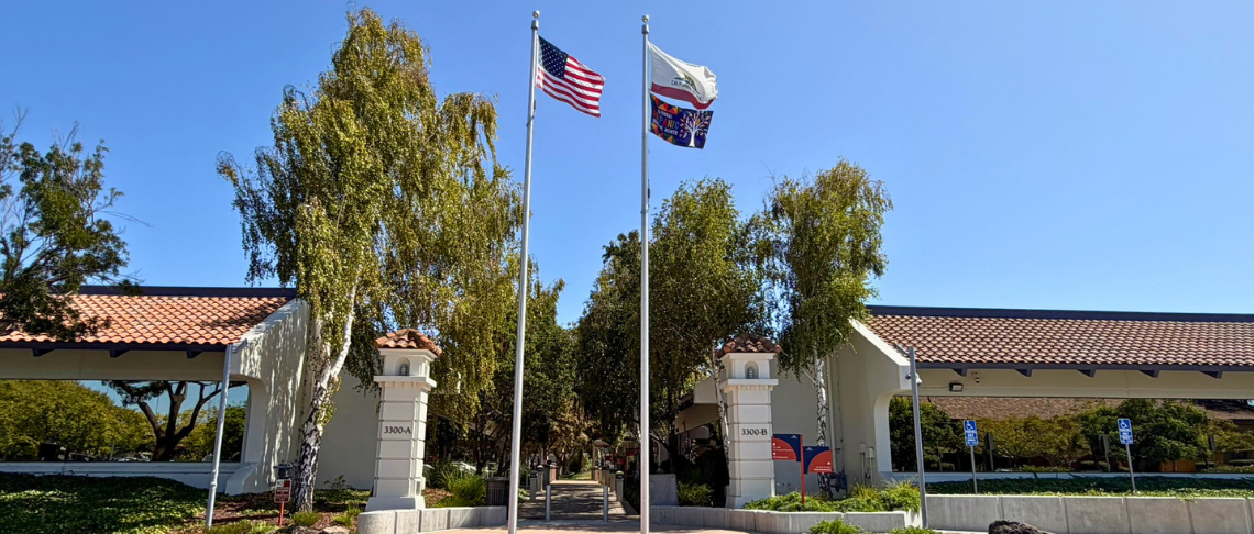 Two flagpoles with the American flag on one and the California and Hispanic Heritage Month flags