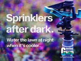 close up photo of a sprinkles with unfocused purple flowers in the background. Text: "sprinklers after dark. water the lawn at night when it's cooler"
