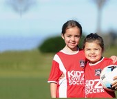 Two girls wearing red soccer jerseys on a green field