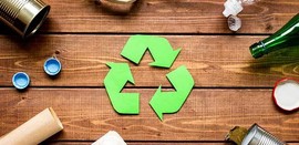 green recycle logo with arrows on a wooden table surrounded by bottles