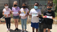 Five kids standing next to one another holding up signs with their names on them