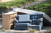 Bulky items including a blue sofa, mattress, and large nightstand on the curb of a street