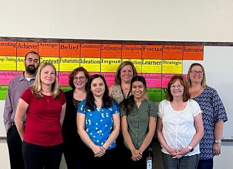 The fiscal team smiling for the camera in front of a colorful background 