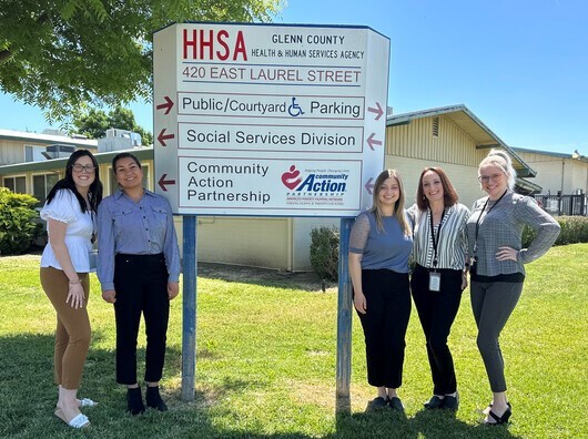 Administration staff smiling for the camera in front of a glenn county health and human services agency building.