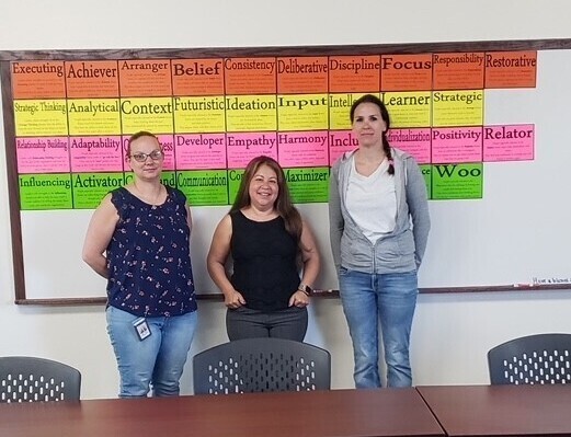 Three fiscal staff members smiling for the camera in front of a colorful background