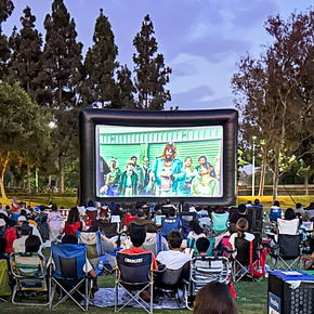 movie screen in a park with a crowd