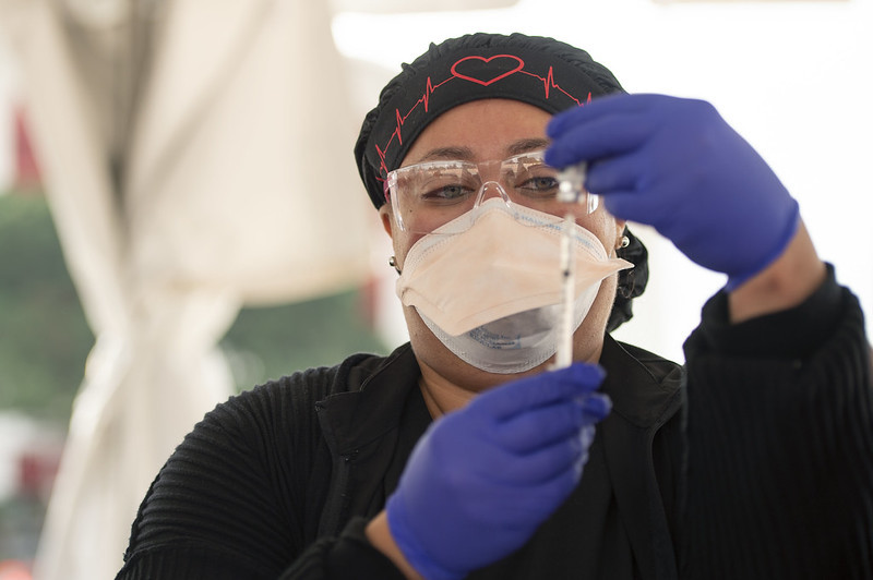 A vaccine administrator prepares a dose for vaccination.