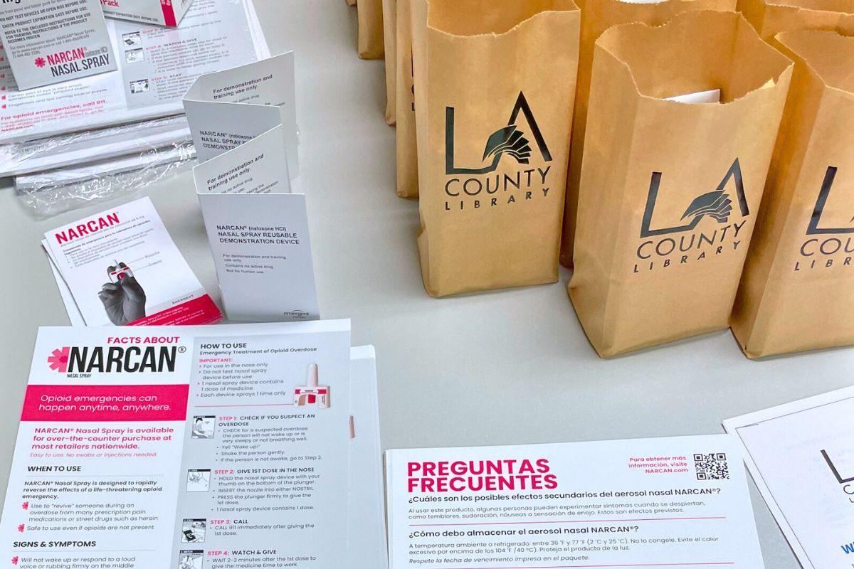 Table with flyers about Narcan bags with LA County Library logo. 