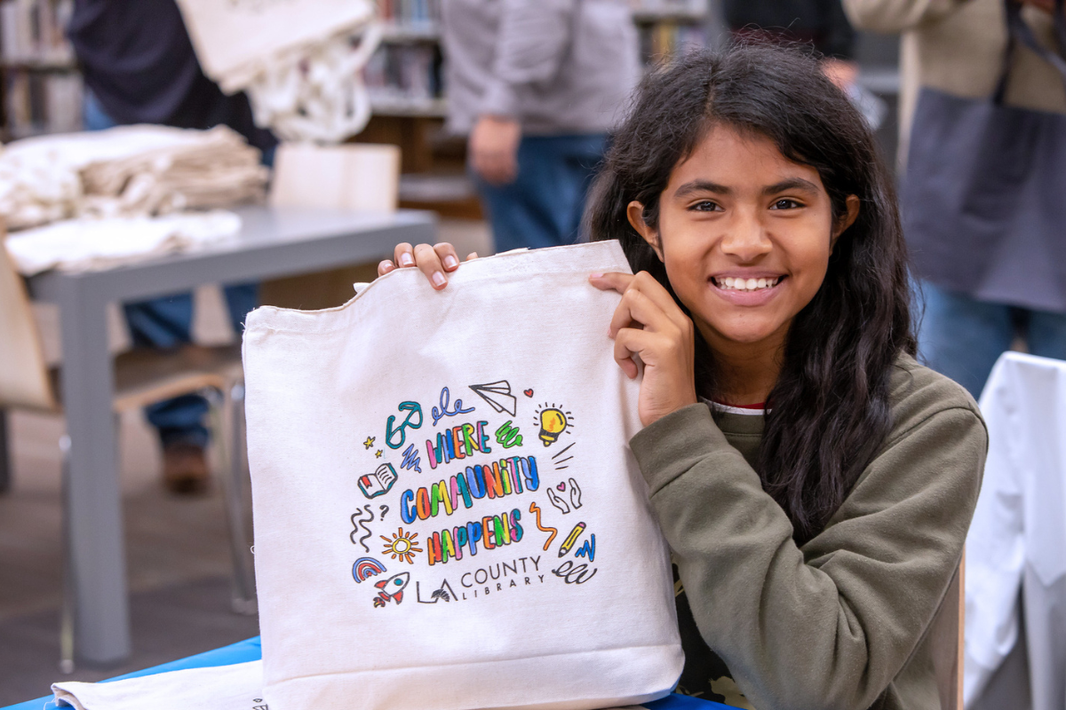 Girl holding bag that reads "Where Community Happens."