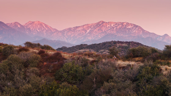 a beautiful view of the San Gabriel Mountain Range with a trail in the foreground and a biker enjoying a cool evening ride 