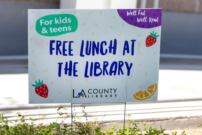 Sign that reads "Well feed well read. For kids and teens. Free lunch at the Library."